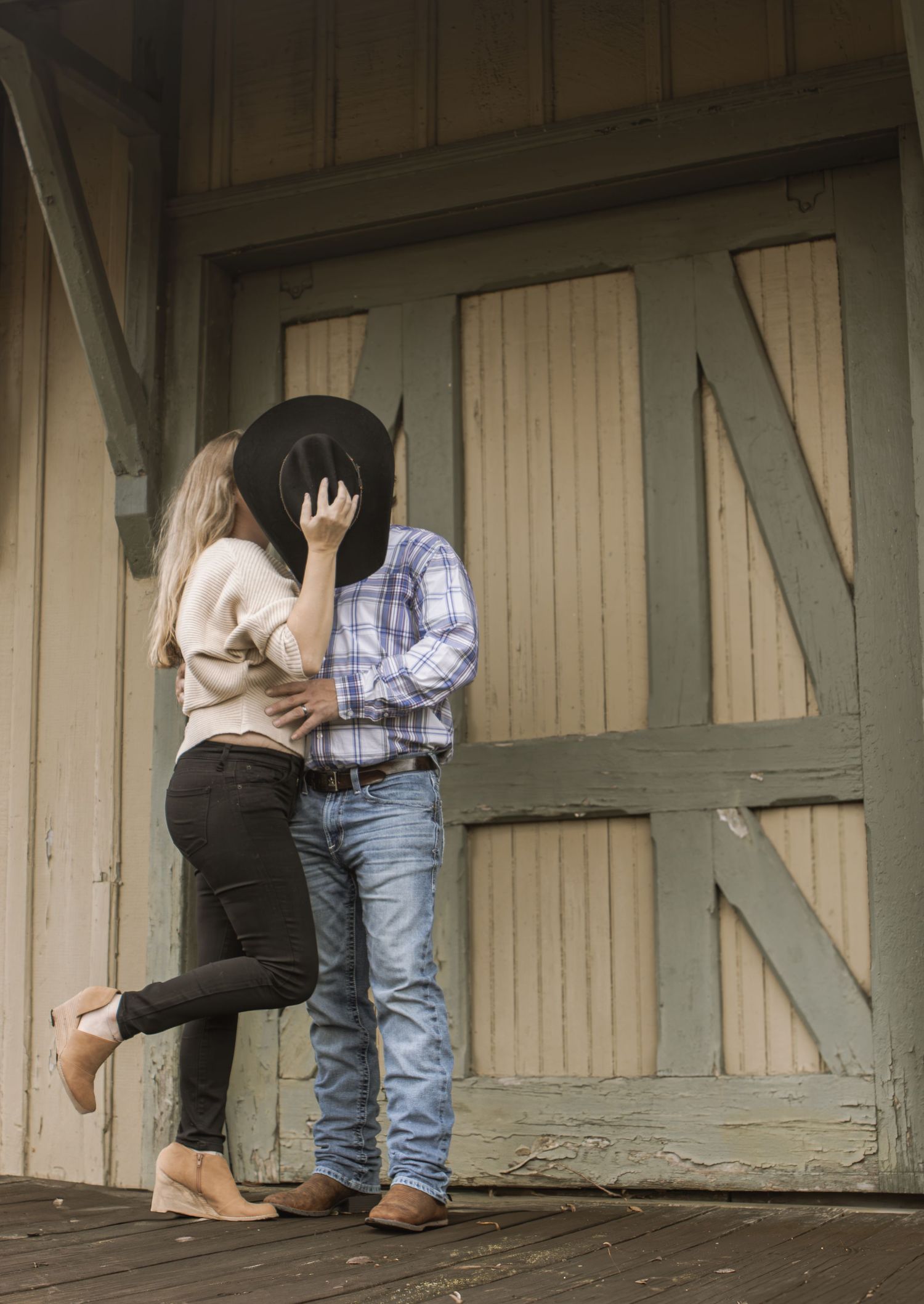 Romantic couple embracing against a rustic barn door.