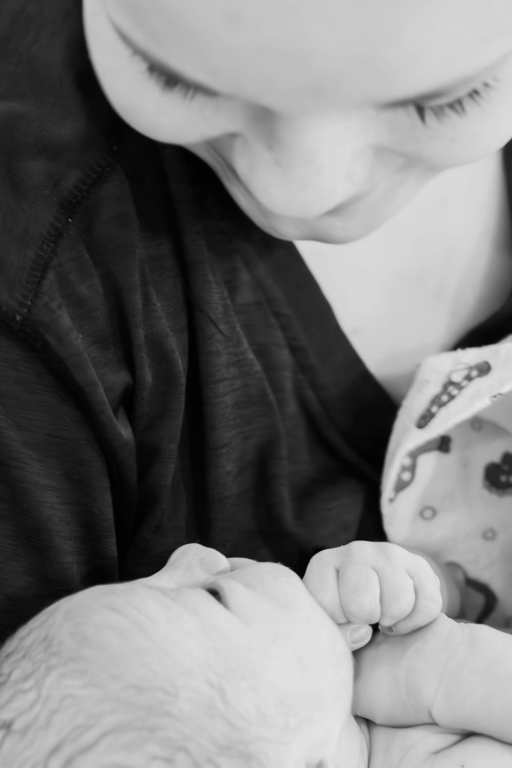 Close-up black and white image of a newborn's tiny hand being held.