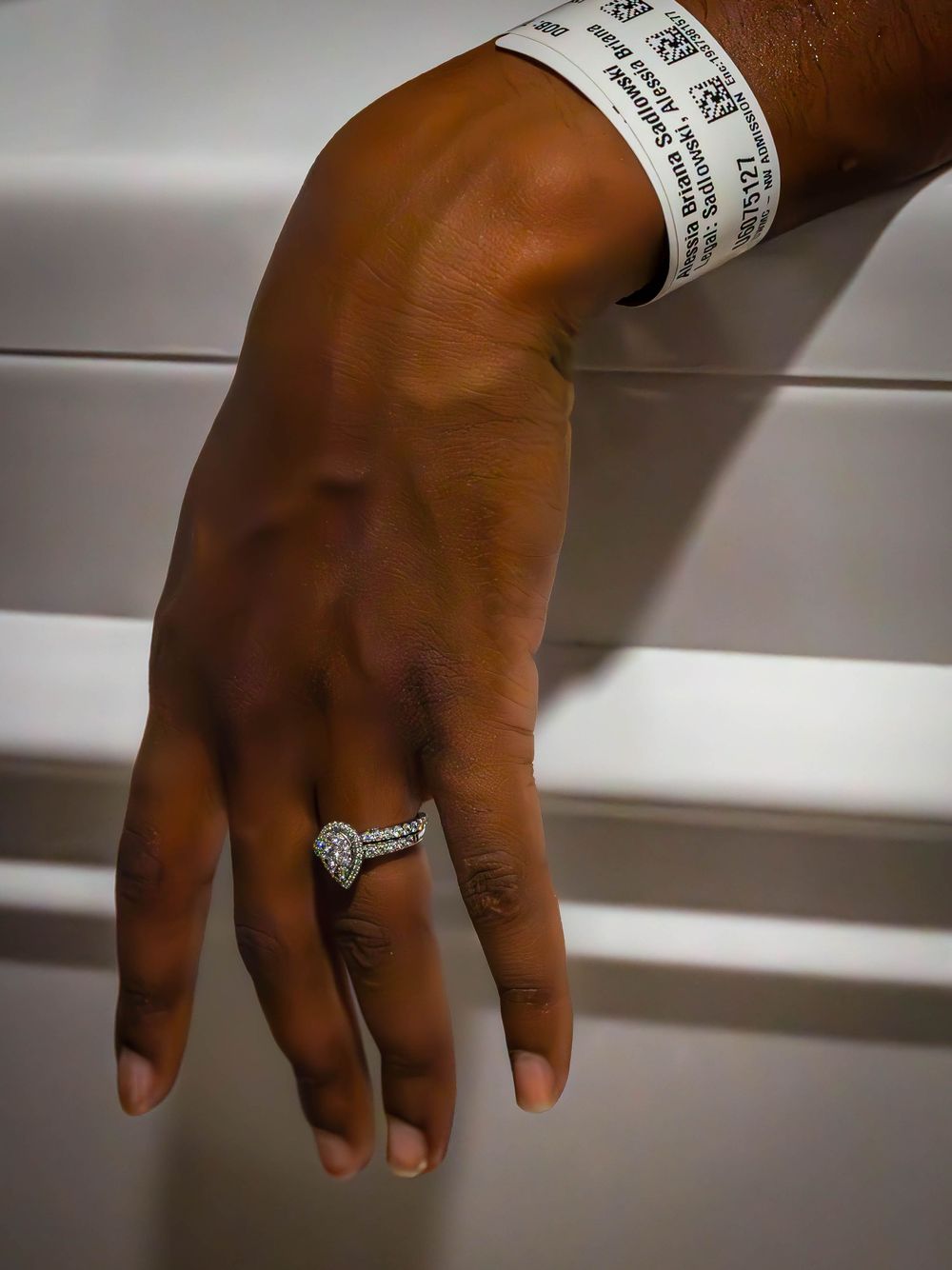 Close-up of hand wearing hospital identification bracelet and diamond ring.