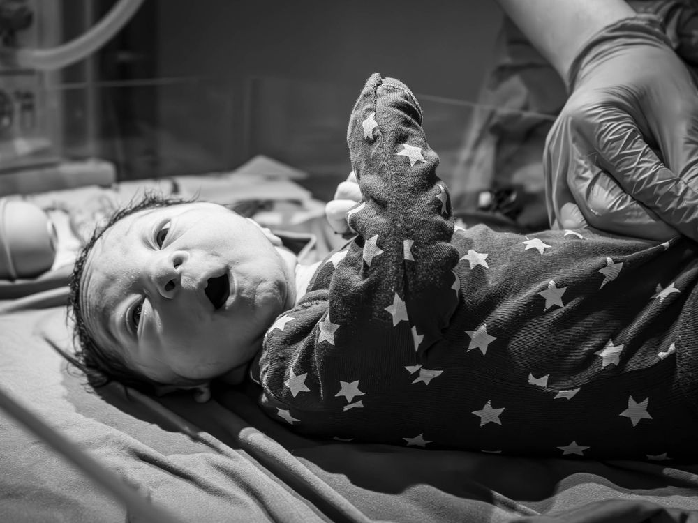 A newborn resting on a hospital bed wearing a star-patterned outfit.