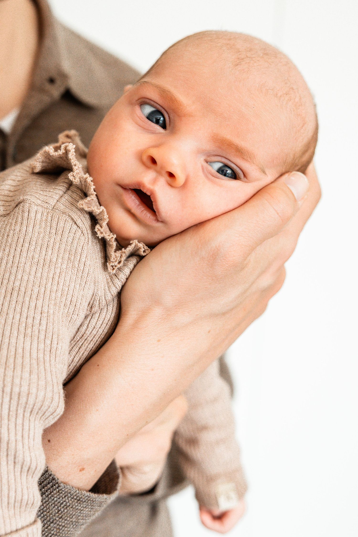 Eerste gezinsfoto met newborn in een lichte ruimte in Herveld, kleurrijk en verhalend gefotografeerd.