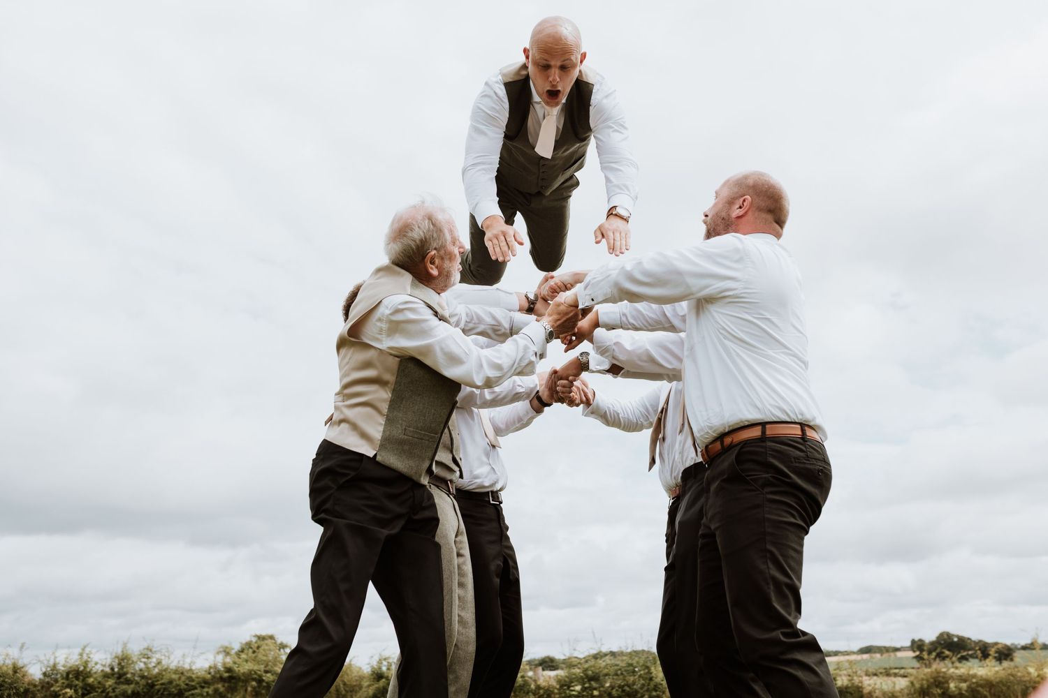 Groomsmen throwing groom in the air on wedding day at Stanford Farm, Shrewsbury