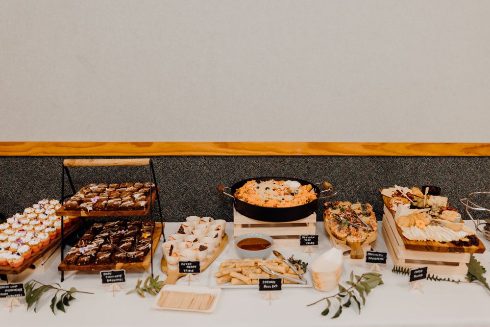 Wedding dessert table with an elegant spread of sweets and treats on dark tablecloths.