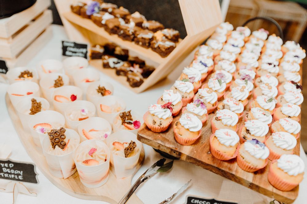 Beautifully arranged wedding cupcakes and desserts displayed on wooden serving boards.