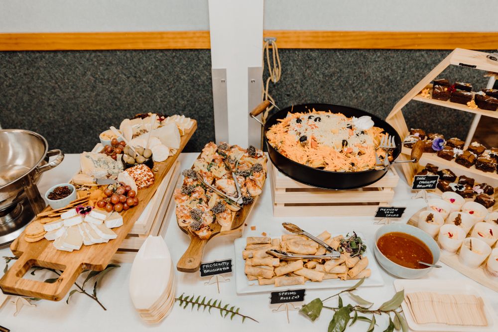 Wedding reception food table with various appetizers and snacks arranged on wooden boards.