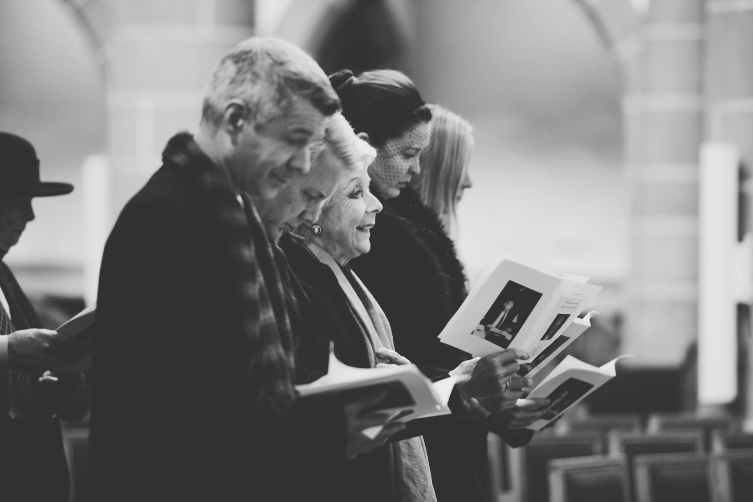 A black and white photograph shows people singing together in a church.