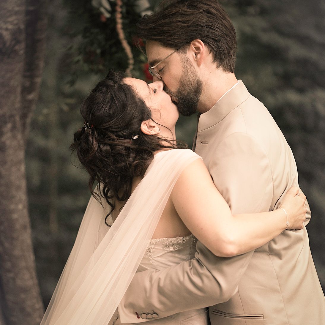 Couple de mariés s’embrassant lors d’une cérémonie laïque en forêt, capturé par un photographe de mariage à Toulouse dans un style naturel