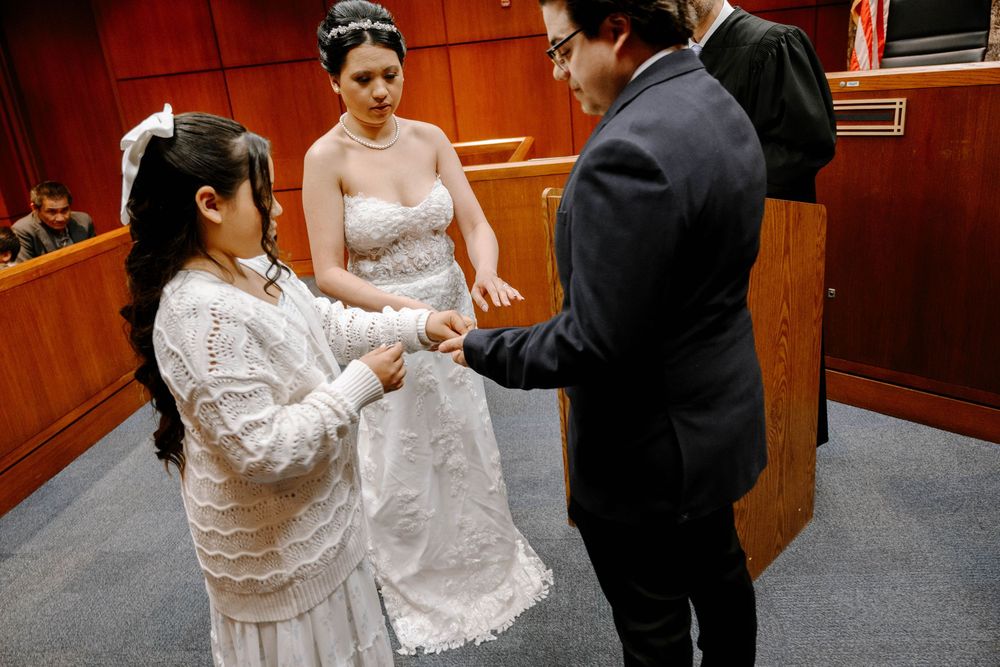 A couple participates in an intimate courtroom wedding ceremony with an officiant present.