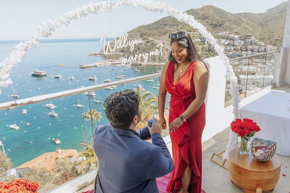 A romantic marriage proposal on a scenic balcony overlooking the blue waters and boats of Catalina Island.