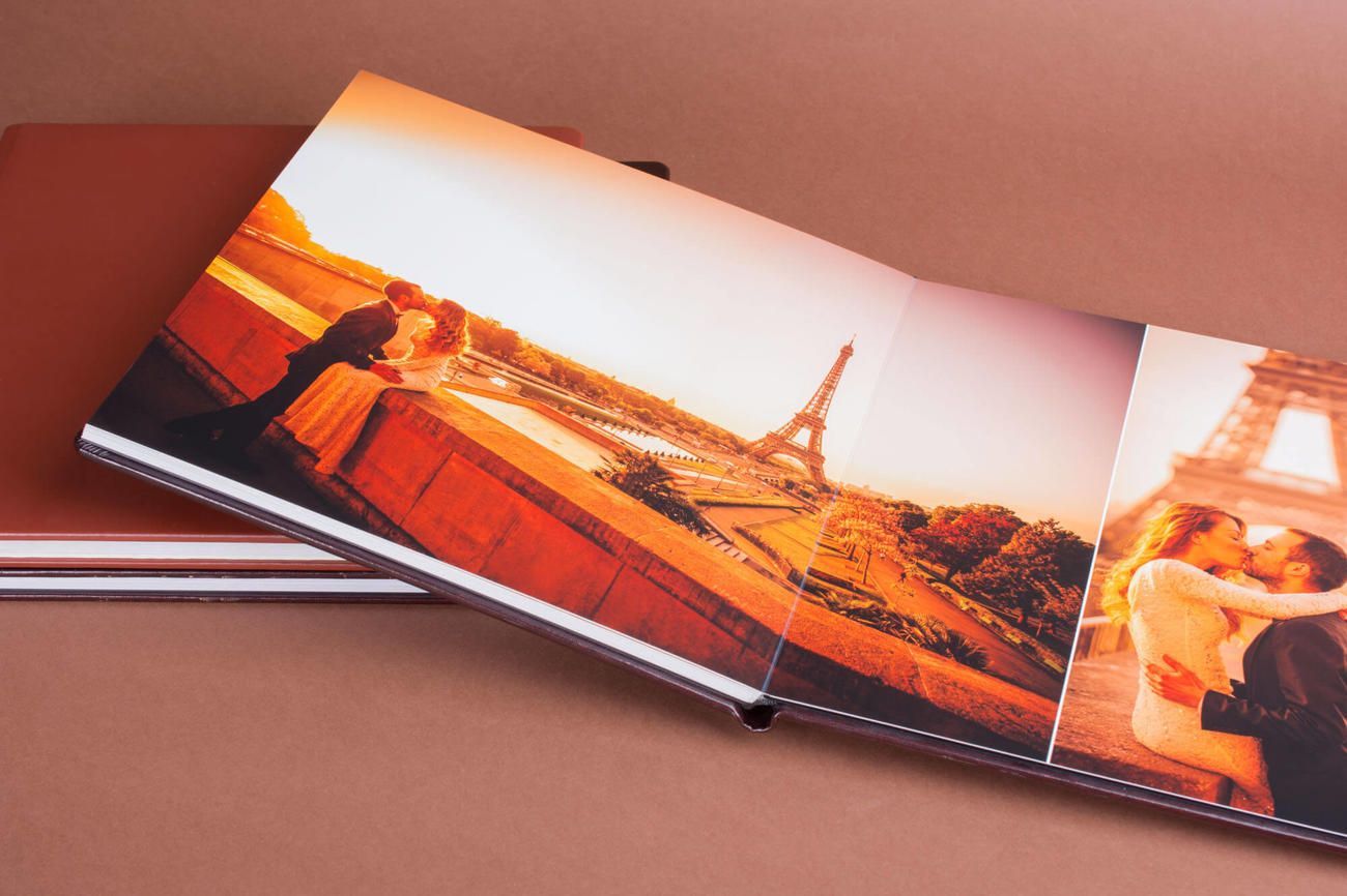 Photo album spread shows warm-toned sunset images of Paris featuring the Eiffel Tower in a romantic layout.