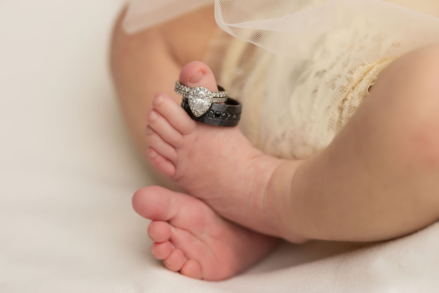 Close-up view of a baby's tiny bare feet with a vintage camera on cream-colored fabric.