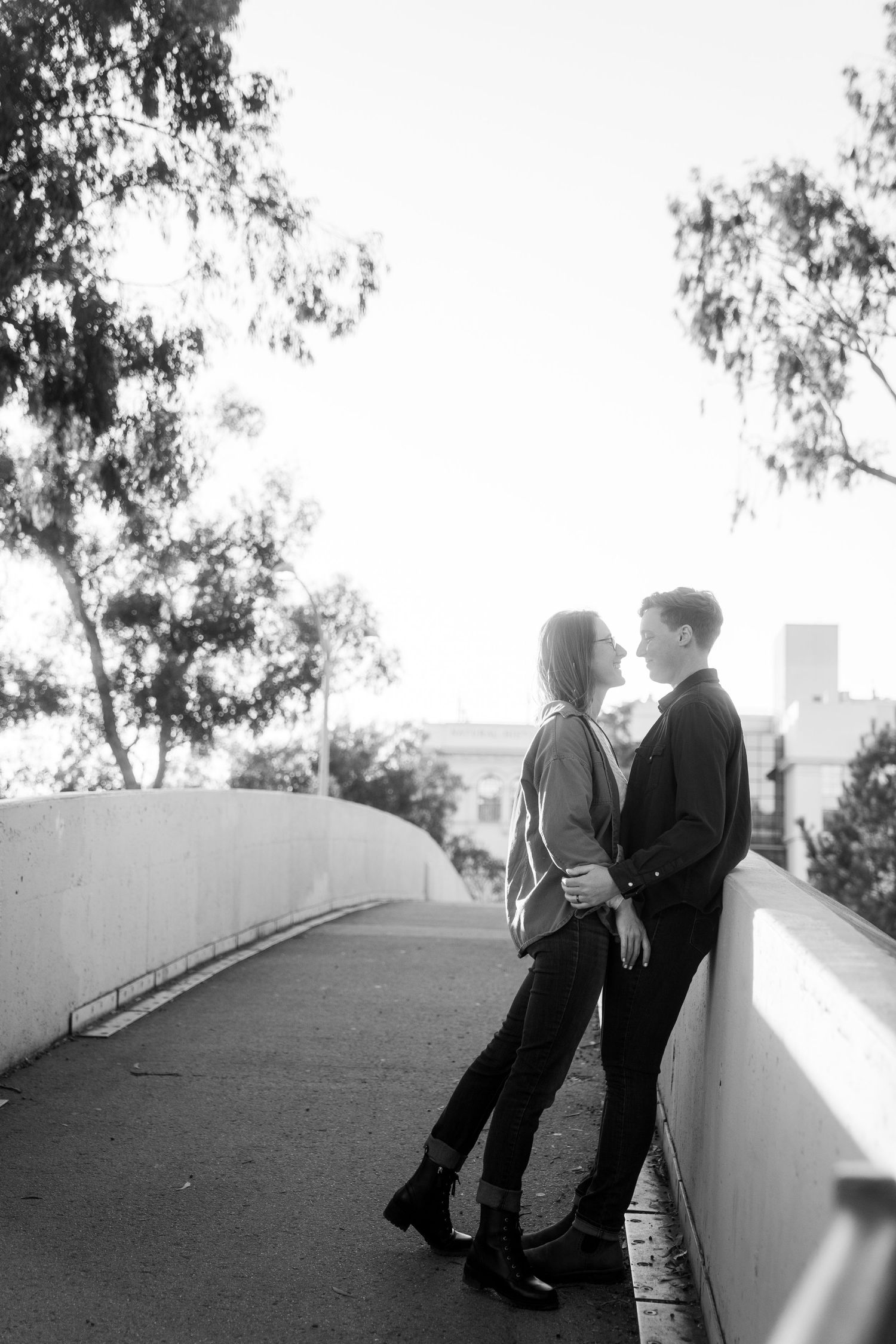 A romantic black and white portrait of a couple sharing an intimate moment on a curved pathway.
