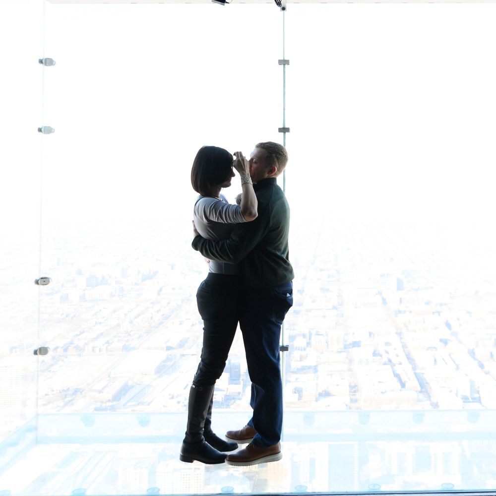Two people in silhouette embrace and share a romantic moment on a bright white background during a winter scene.