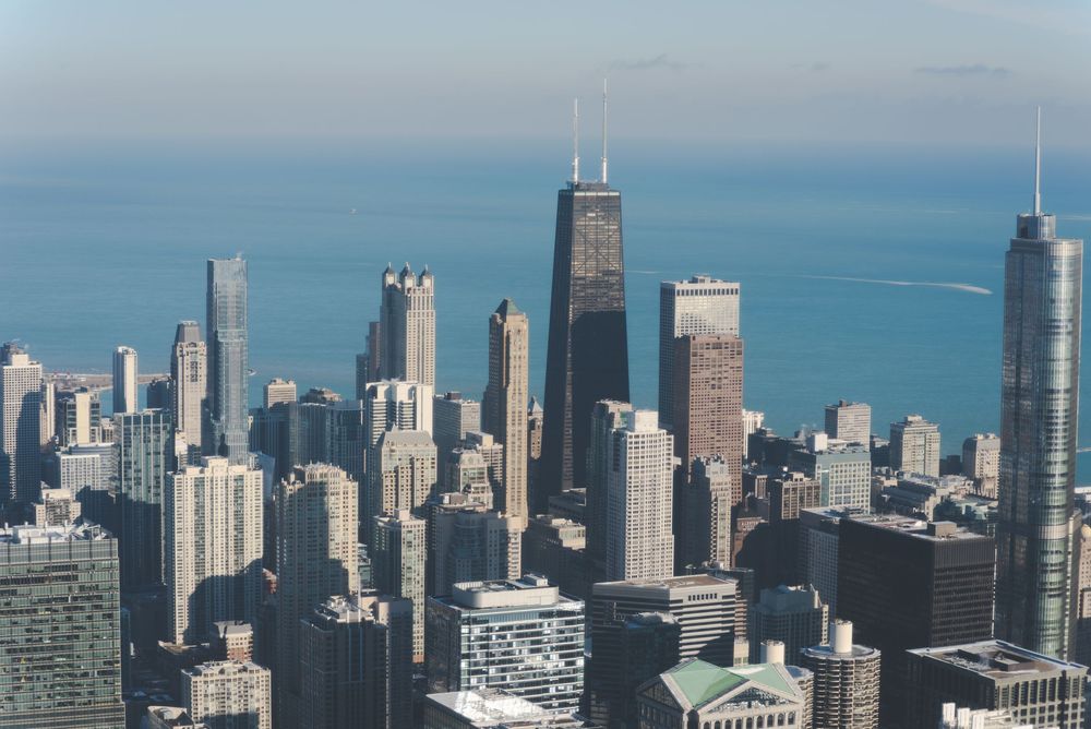 Aerial view of Chicago skyline featuring the John Hancock Center and downtown skyscrapers against Lake Michigan.