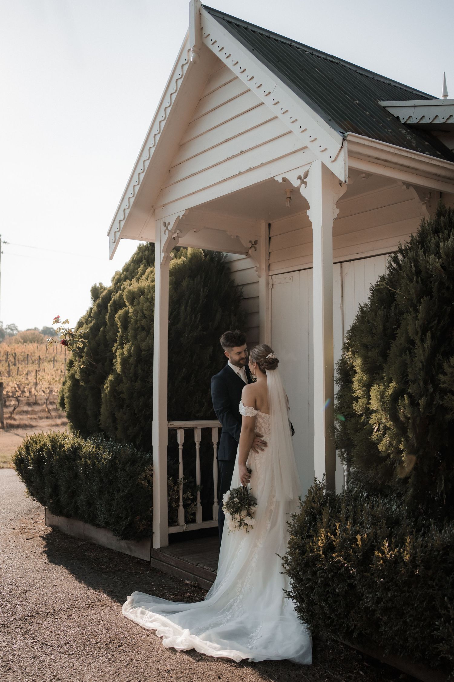 A romantic moment captured under a white gazebo surrounded by greenery.