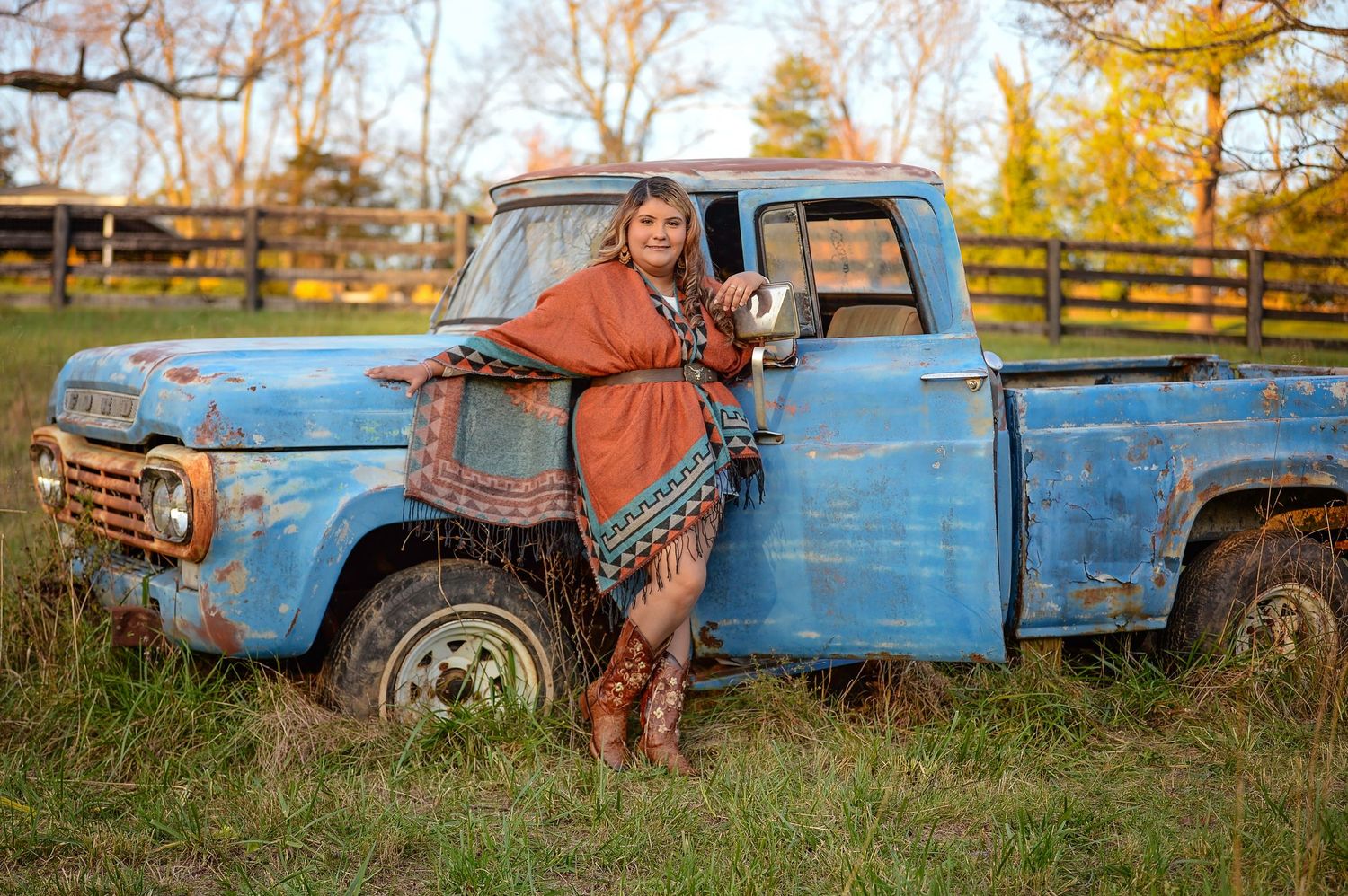 Professional photo session featuring rustic blue vintage truck with fall foliage in the background makes for a romantic setting.
