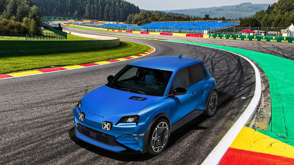 Electric blue Volvo C40 Recharge electric SUV racing around a colorful track curve with mountains in the background.