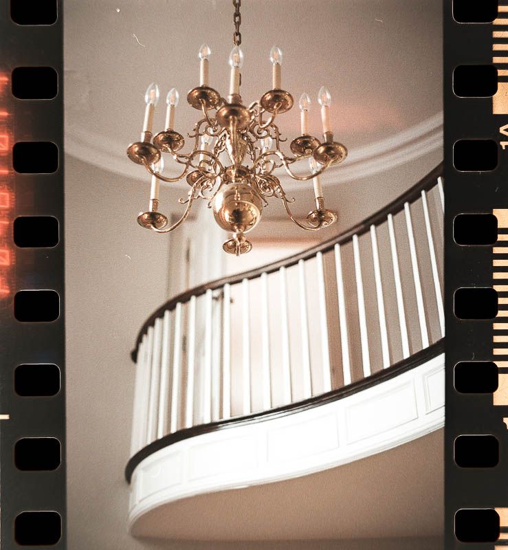 Wedding Photo chandelier hangs above a curved white staircase Christ First Church Fox Chapel PA Near Pittsburgh Shot on 35mm Film