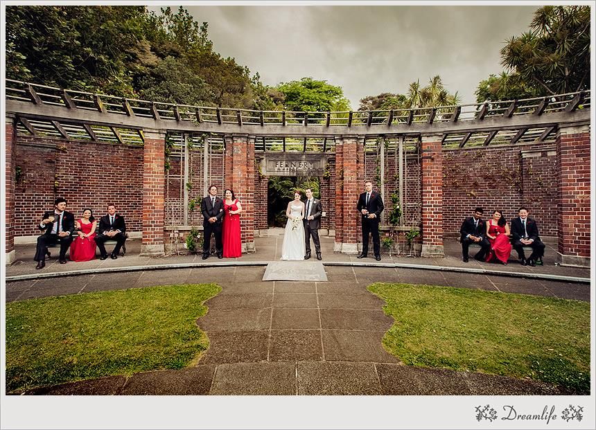 Wedding party in formal attire poses in a brick courtyard with symmetrical archways at historic venue.