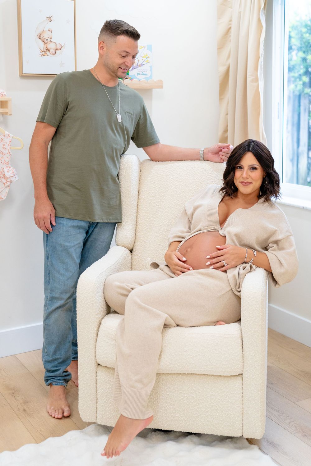A couple shares a tender moment in a bright living room as they relax in a cream-colored armchair.