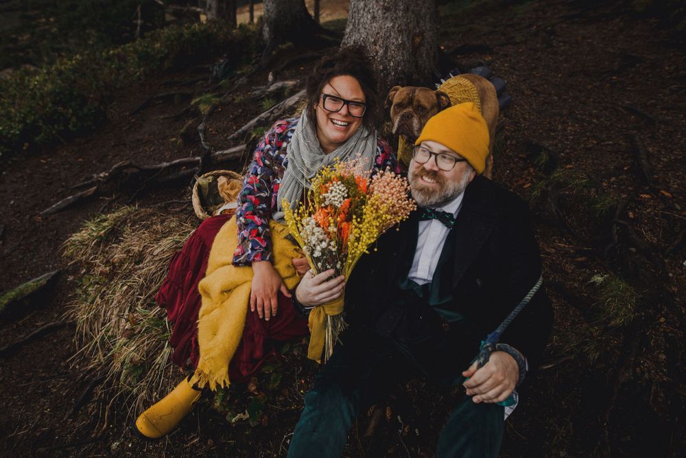 Couple shares intimate moment with floral bouquet on autumn forest trail.
