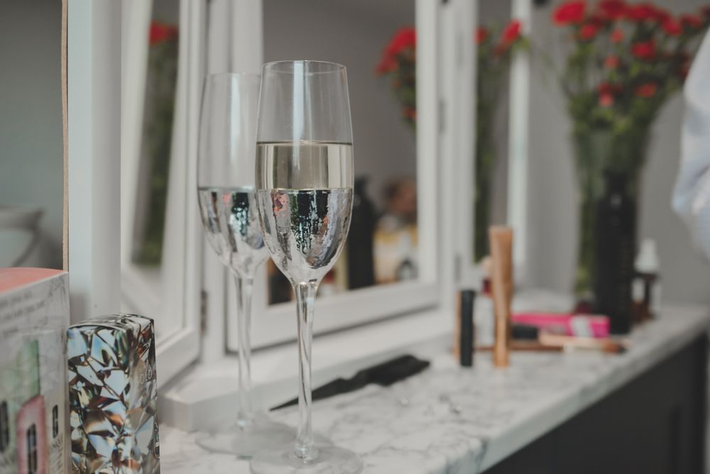 Wedding reception detail of champagne glasses and red flowers on marble counter.
