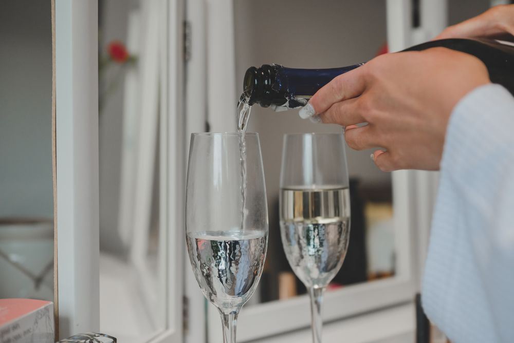 Champagne being poured into elegant flute glasses at wedding celebration.
