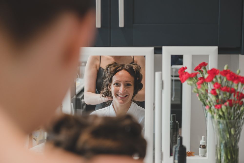 Getting ready scene reflected in mirror with red flowers in background.