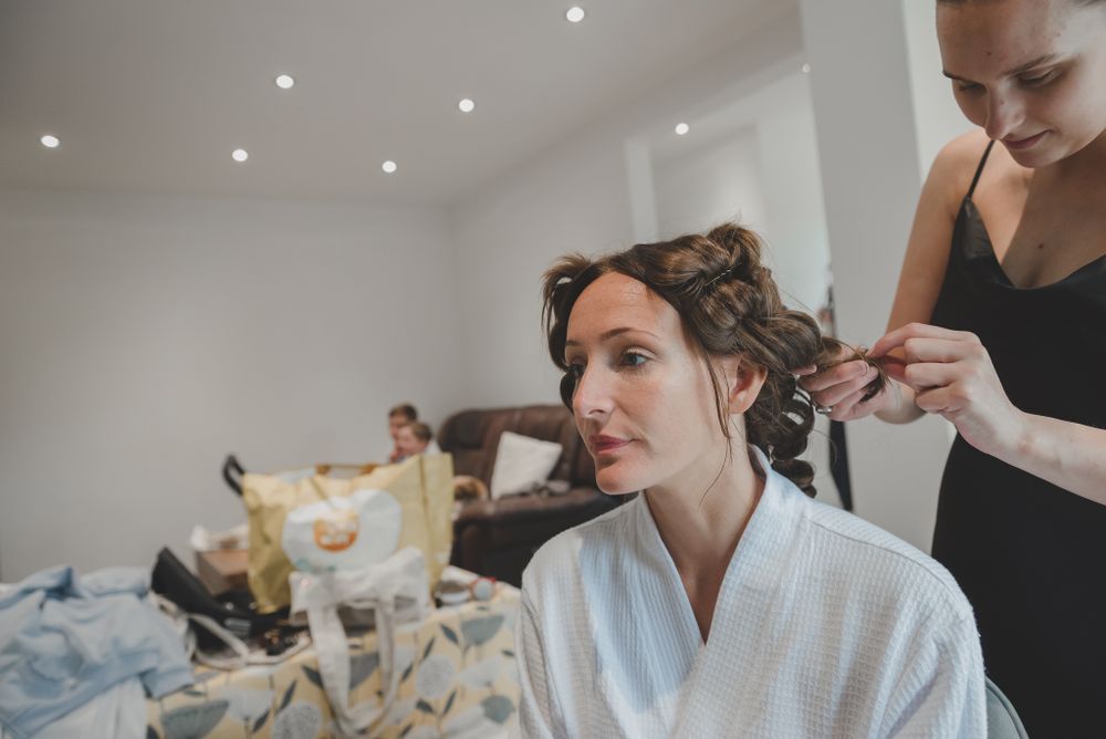 Wedding preparation scene with hairstyling in bright white room.