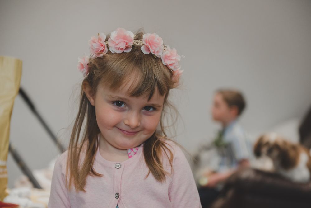 Young attendant wearing pink floral crown at formal event.