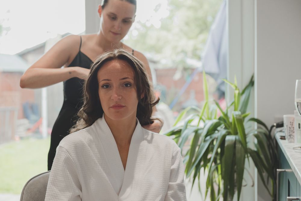 Professional hairstylist works on client's hair in bright salon setting.