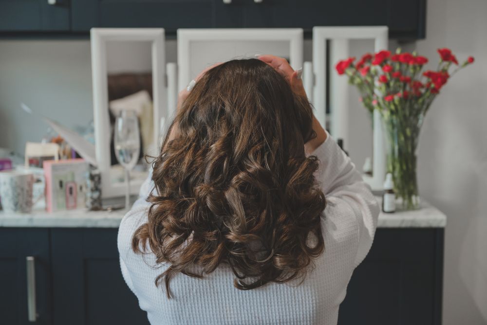 Back view of styled brunette hair with bouncy curls and red hair accessory.