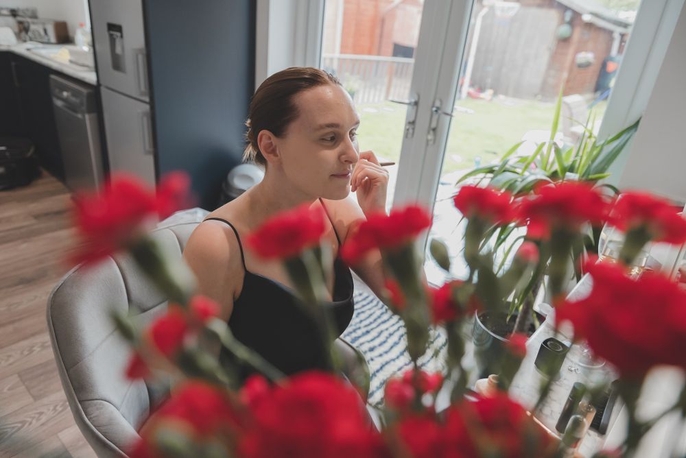 Person seated with red carnations in foreground of modern interior setting.