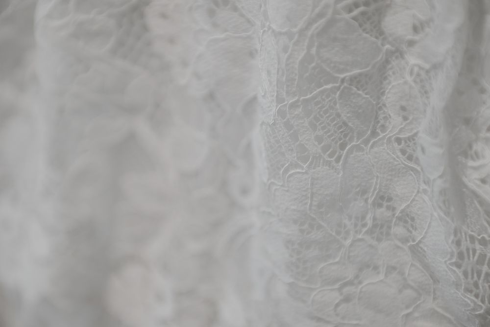 Macro shot of intricate floral lace pattern on white wedding dress material.