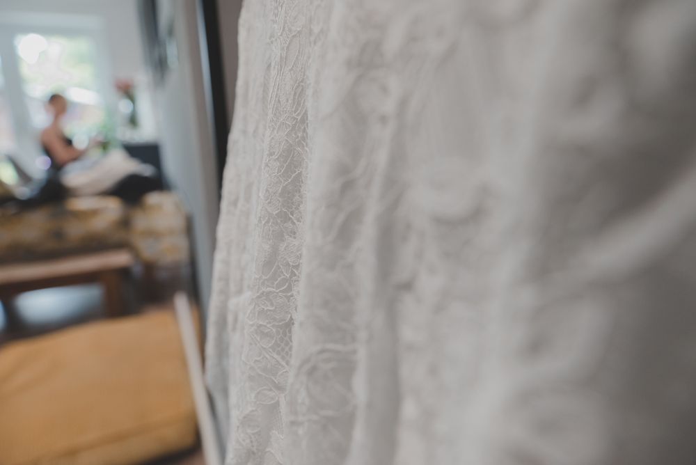 Close-up detail of delicate white lace wedding dress fabric with soft bokeh background.
