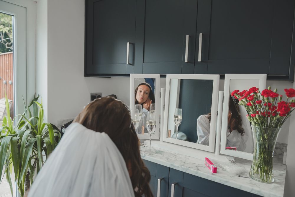 Modern dressing room setup with trifold mirror and red carnations in vase.