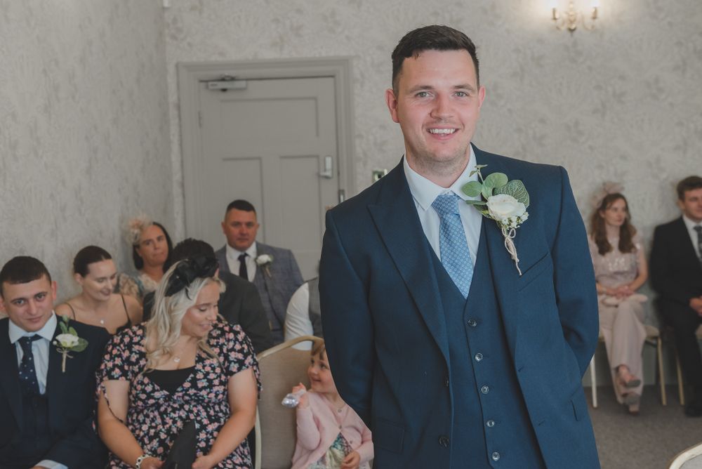 A formal ceremony taking place in an elegant room with wallpapered walls.