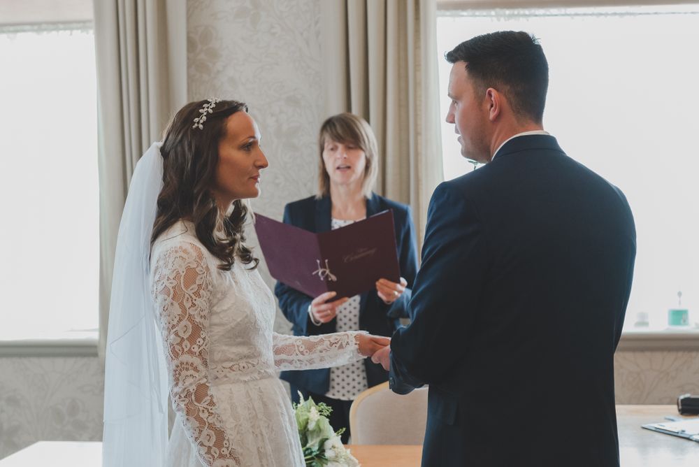 Wedding ceremony in progress with officiant leading the service in a bright indoor venue.