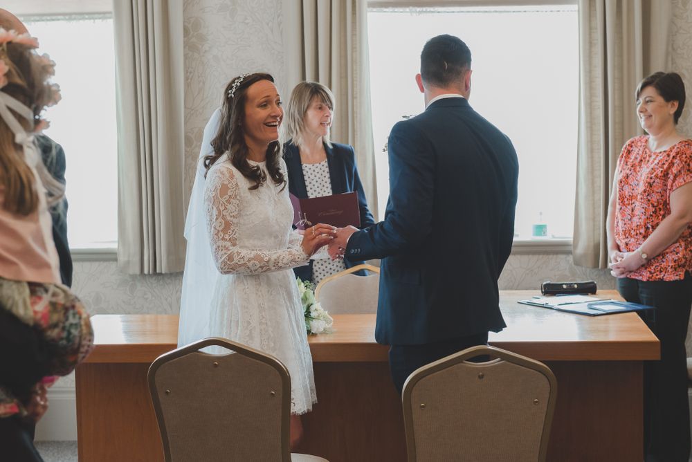Wedding ceremony taking place in a simple room with guests watching the proceedings.