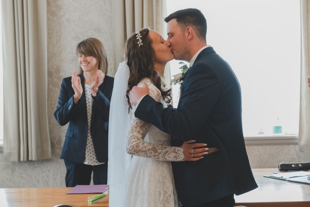 Newlyweds share their first kiss as a married couple during indoor ceremony.