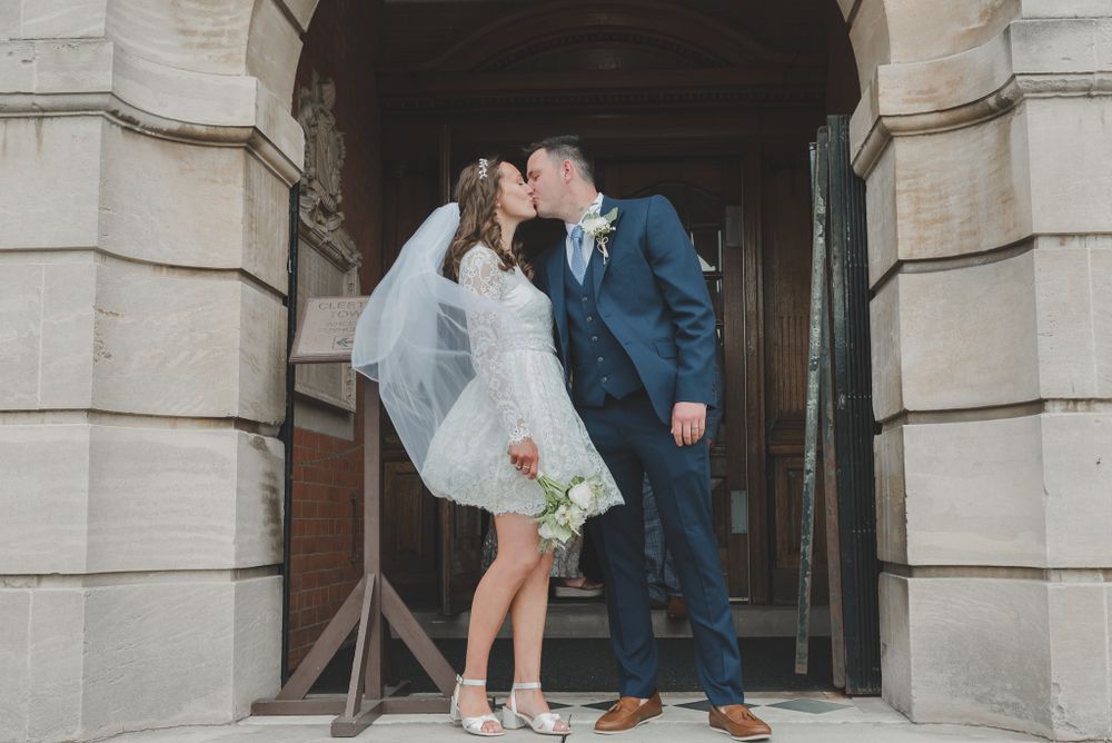 Romantic moment captured in stone archway during wedding photoshoot.
