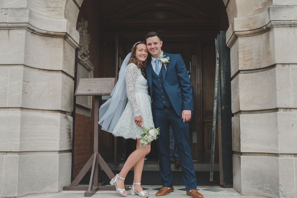 Newlyweds pose together in historic stone archway for wedding portraits.