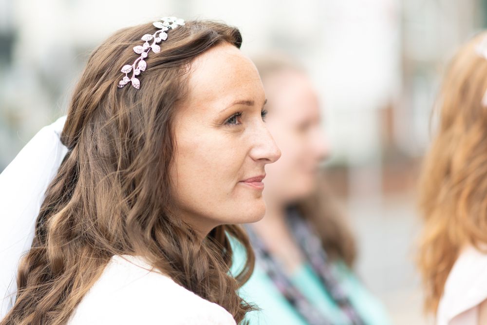 A delicate silver tiara adorns long wavy brown hair on a sunny day.