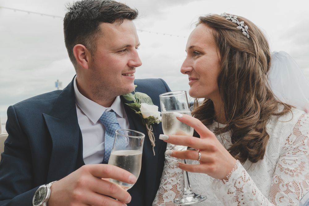Newlyweds share a toast with champagne glasses while exchanging loving glances.