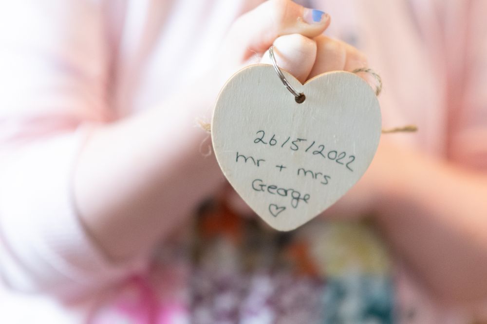 A white heart-shaped tag displays a wedding date detail in soft focus.