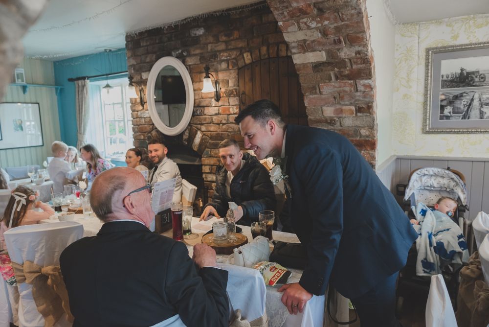 Guests socializing at a wedding reception with exposed brick walls and elegant table settings.