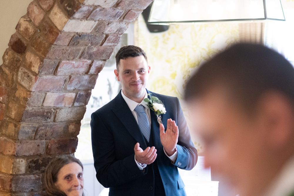 Wedding guest giving speech under rustic brick archway at reception.