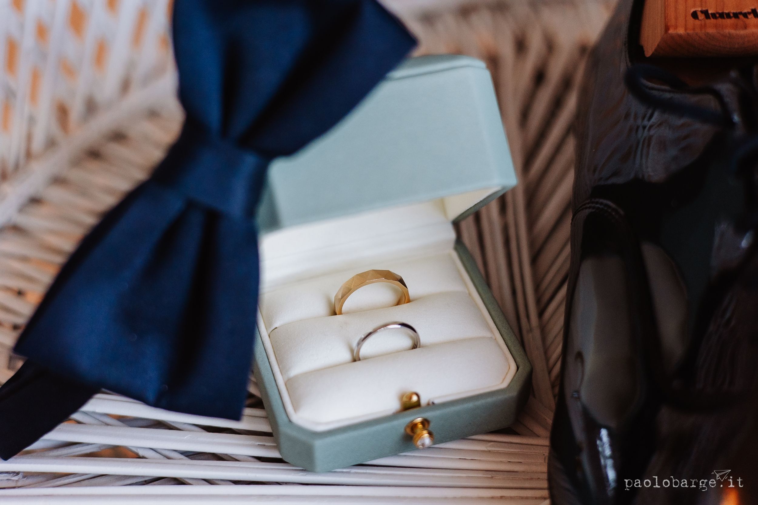 Close-up view of an elegant white engagement ring box with a gold clasp displayed on textured surfaces.