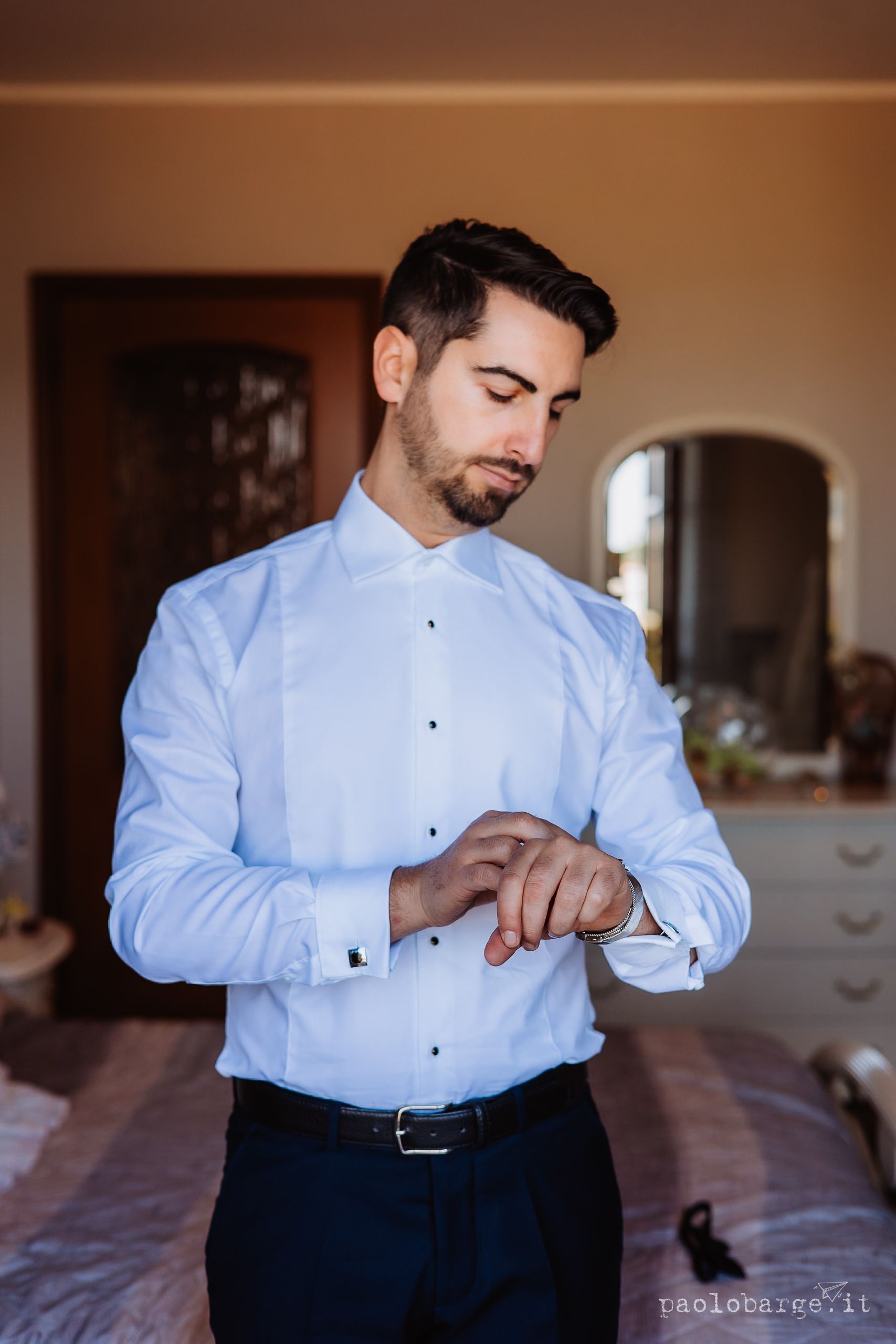 A sequence of shots showing someone in a light blue dress shirt fastening cufflinks and preparing formal attire.
