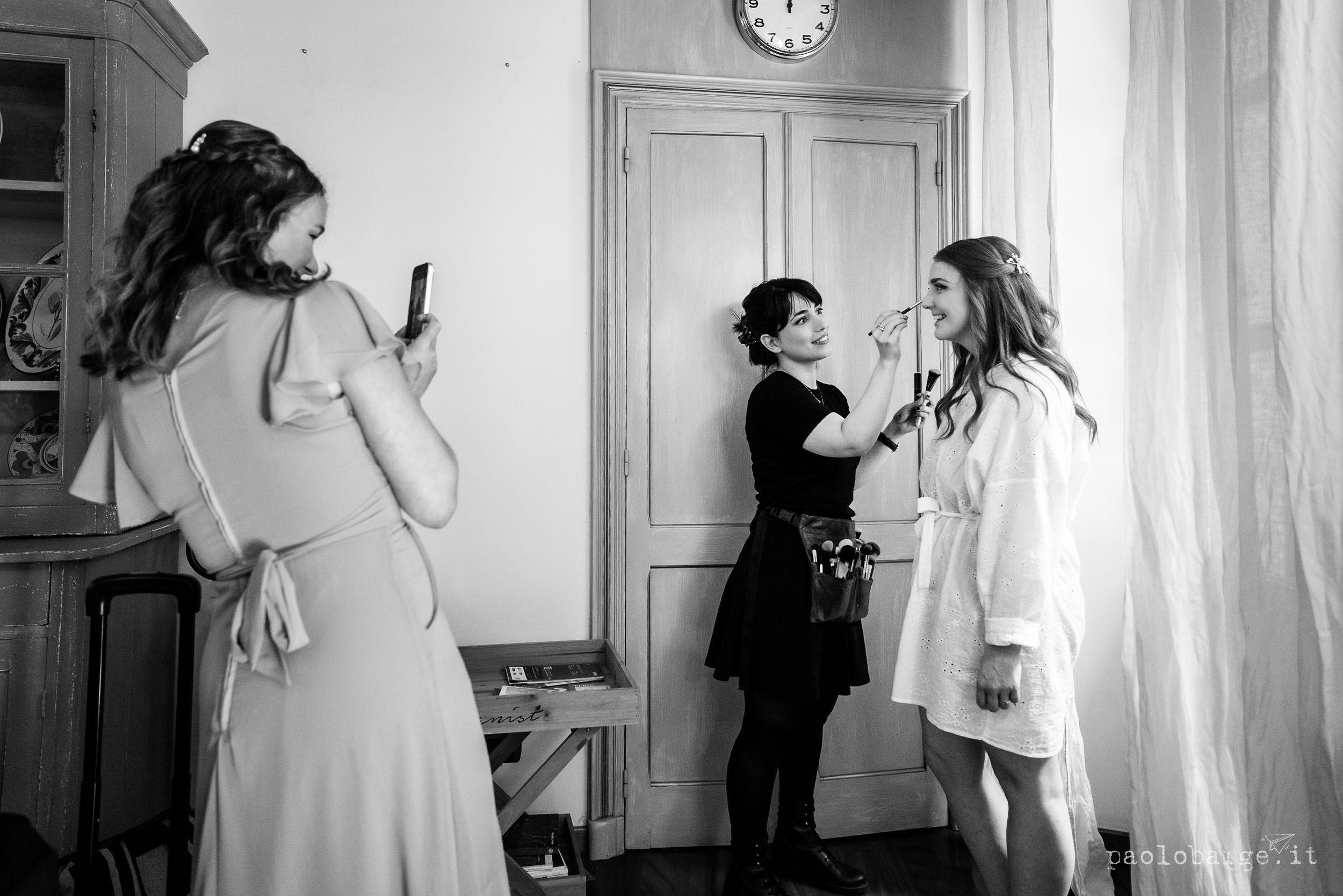 People gather in an elegant room preparing for a special occasion in this black and white candid moment.